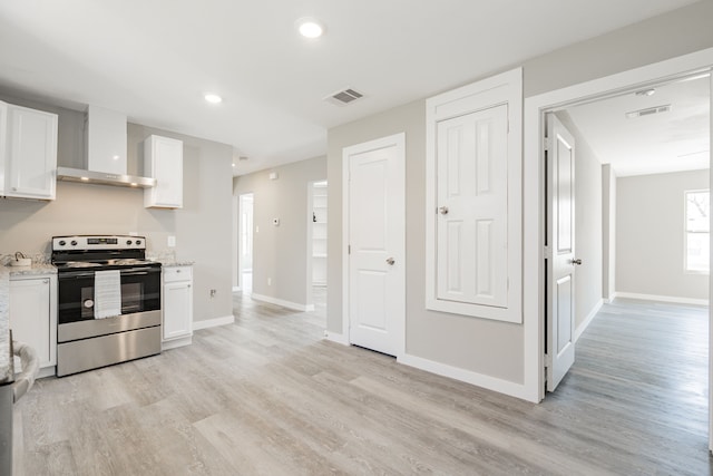 kitchen featuring visible vents, wall chimney range hood, stainless steel electric stove, white cabinets, and light wood finished floors