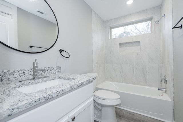 full bathroom with tiled shower / bath, vanity, toilet, and wood-type flooring