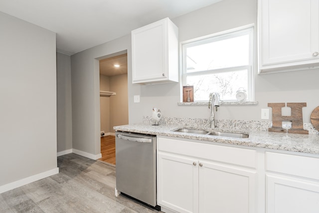 kitchen featuring dishwasher, white cabinets, light stone countertops, and a sink