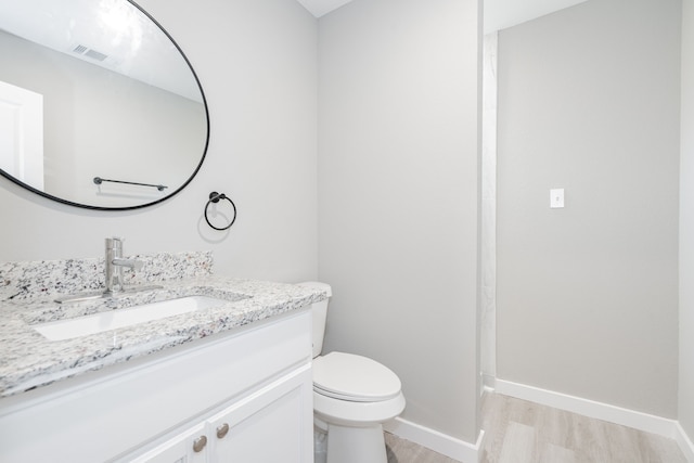 bathroom with hardwood / wood-style flooring, vanity, and toilet