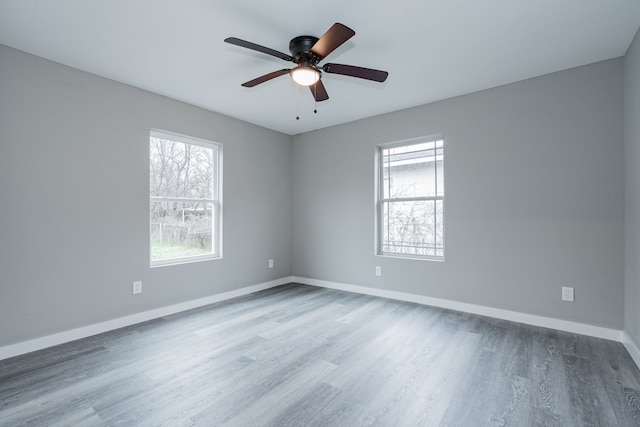 unfurnished room featuring wood finished floors, a healthy amount of sunlight, baseboards, and ceiling fan