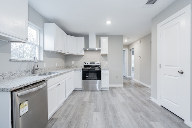 kitchen with light stone countertops, appliances with stainless steel finishes, sink, wall chimney range hood, and white cabinets