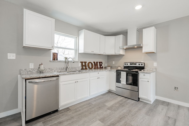 kitchen featuring white cabinets, appliances with stainless steel finishes, wall chimney exhaust hood, and a sink