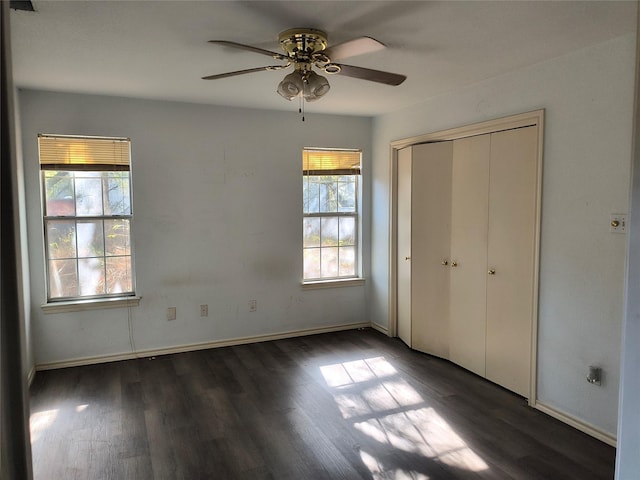 unfurnished bedroom featuring ceiling fan, a closet, dark wood-type flooring, and multiple windows