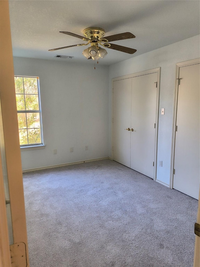 unfurnished bedroom with ceiling fan, a closet, and light carpet