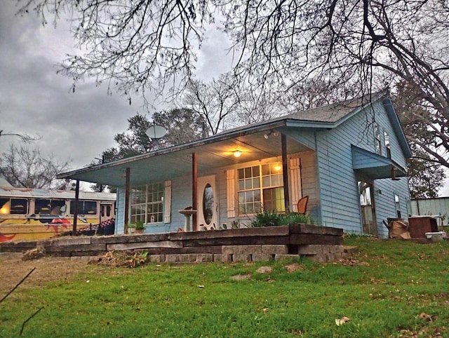 rear view of house featuring a porch and a lawn