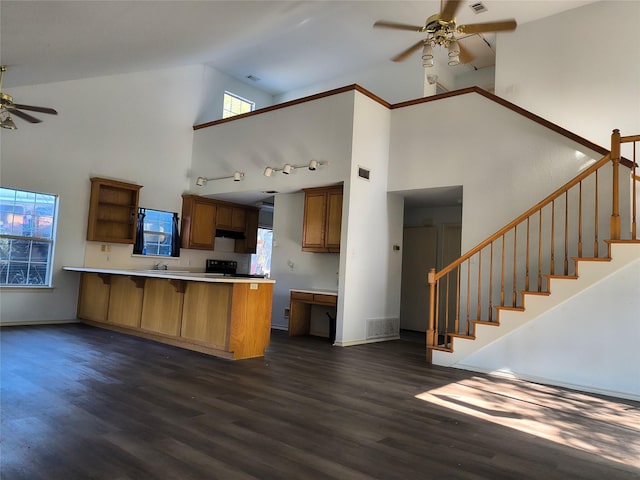 kitchen with a breakfast bar, kitchen peninsula, dark wood-type flooring, and high vaulted ceiling