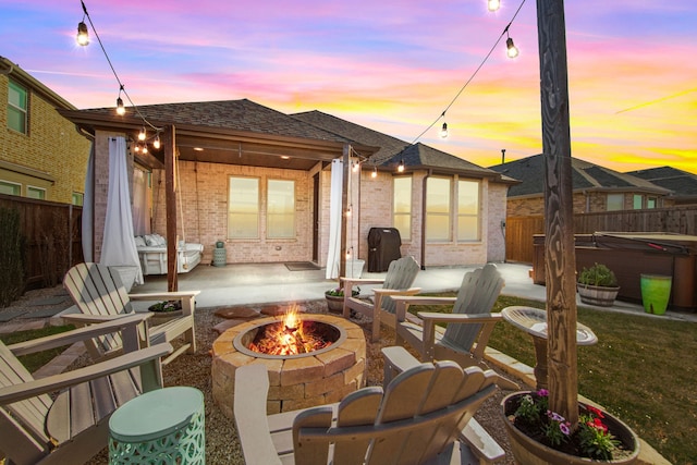 patio terrace at dusk featuring a hot tub and a fire pit