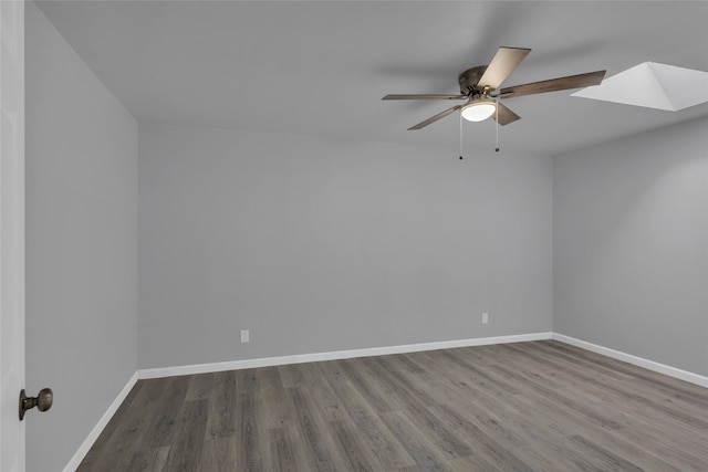 spare room featuring ceiling fan, a skylight, and hardwood / wood-style floors