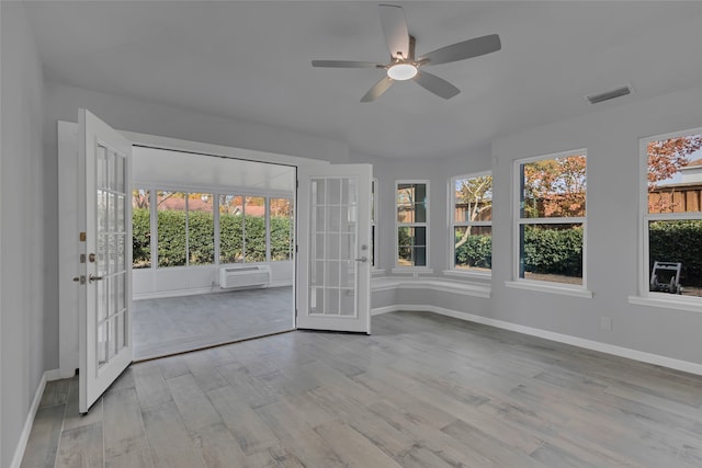 unfurnished sunroom with a wall unit AC, ceiling fan, and french doors