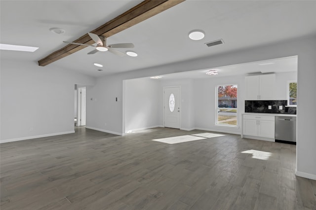 unfurnished living room with ceiling fan, beam ceiling, a skylight, and light wood-type flooring