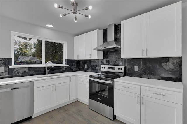 kitchen with white cabinets, appliances with stainless steel finishes, wall chimney exhaust hood, decorative backsplash, and sink