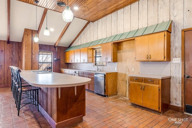 kitchen with dishwasher, sink, lofted ceiling with beams, wood walls, and pendant lighting