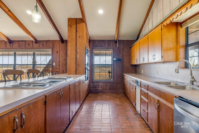 kitchen with beamed ceiling, sink, wooden walls, and stainless steel appliances