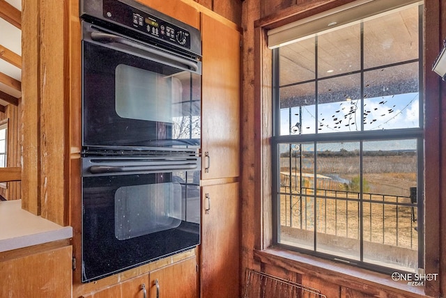 kitchen with wooden walls and black double oven