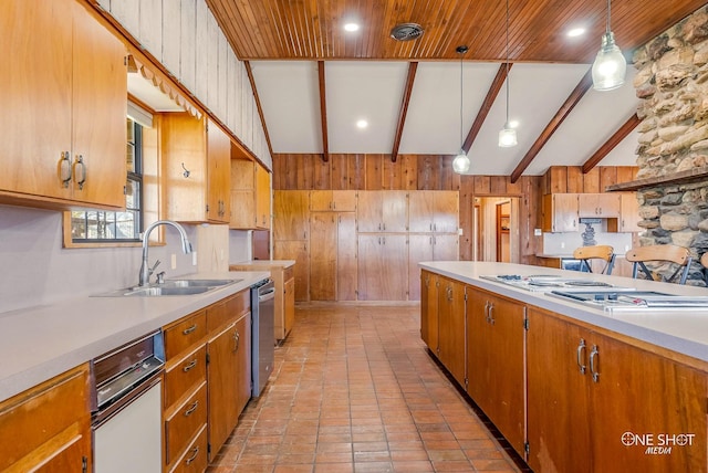 kitchen featuring wooden walls, decorative light fixtures, sink, and vaulted ceiling with beams