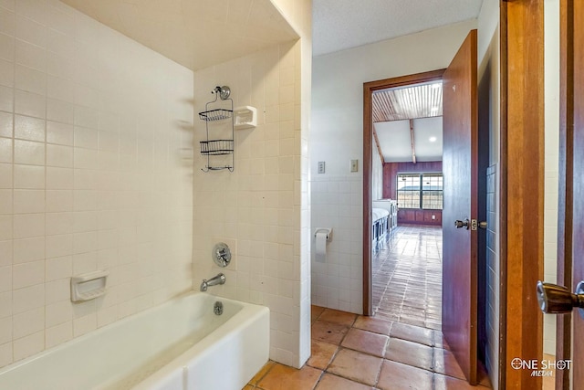 bathroom featuring tile patterned flooring, tiled shower / bath combo, and tile walls