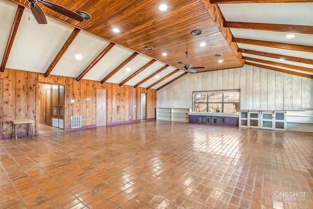 unfurnished living room featuring ceiling fan, lofted ceiling with beams, wooden ceiling, tile patterned flooring, and wood walls