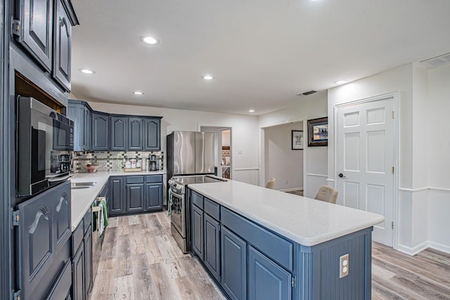 kitchen featuring backsplash, a kitchen island, stainless steel appliances, blue cabinets, and light wood-type flooring