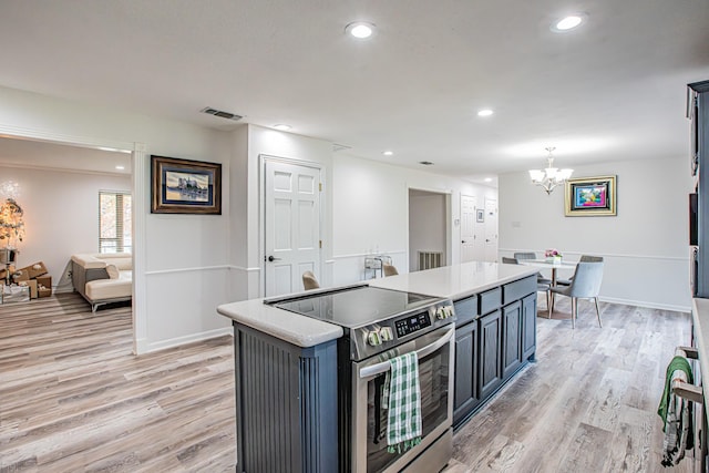 kitchen featuring stainless steel range with electric stovetop, hanging light fixtures, an inviting chandelier, a center island, and light wood-type flooring