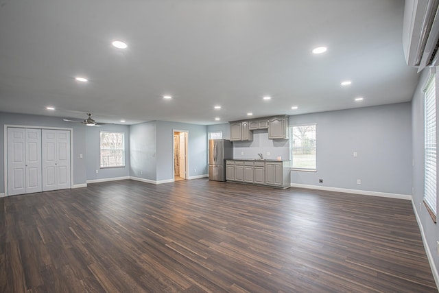 unfurnished living room featuring dark hardwood / wood-style floors, sink, and ceiling fan