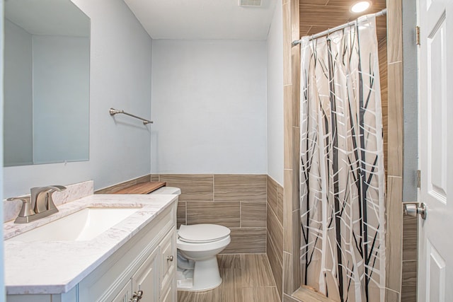 bathroom with tile walls, vanity, toilet, and a shower with shower curtain