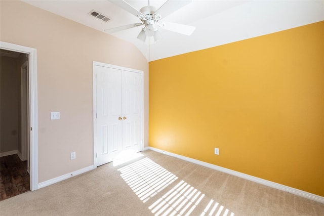 unfurnished bedroom with ceiling fan, vaulted ceiling, light carpet, and a closet