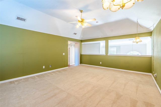 spare room featuring carpet flooring, ceiling fan with notable chandelier, and vaulted ceiling