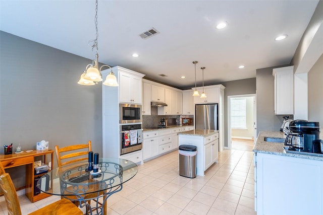 kitchen with stainless steel appliances, a kitchen island, sink, decorative light fixtures, and white cabinetry