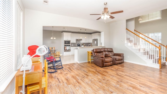 living room with light hardwood / wood-style flooring and ceiling fan with notable chandelier