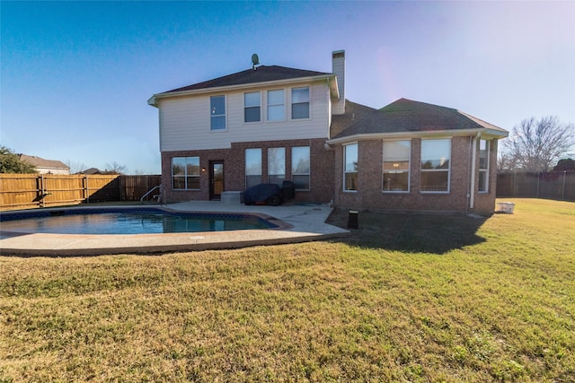 rear view of house with a fenced in pool and a yard