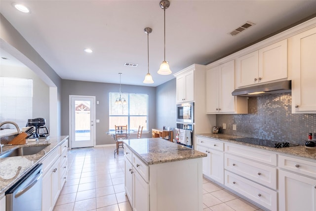 kitchen with appliances with stainless steel finishes, a kitchen island, sink, pendant lighting, and white cabinetry