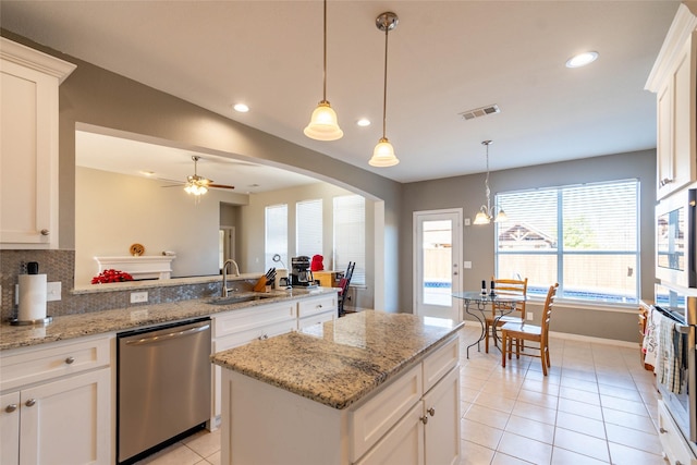 kitchen featuring a center island, sink, light stone countertops, appliances with stainless steel finishes, and white cabinetry