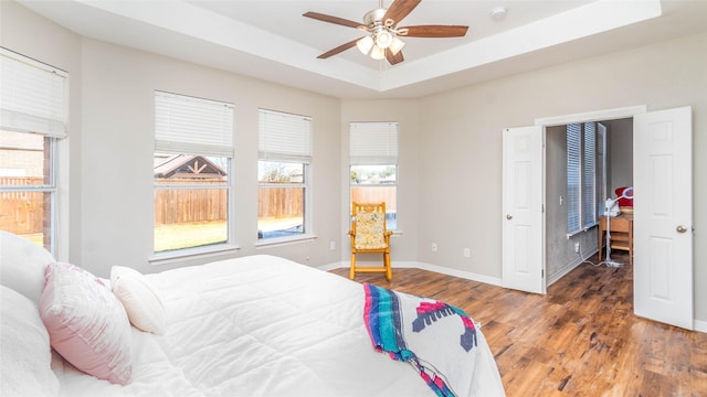 bedroom featuring ceiling fan, a raised ceiling, and dark wood-type flooring