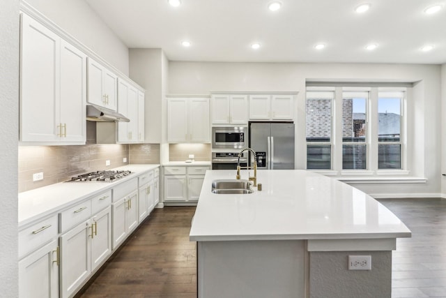 kitchen with appliances with stainless steel finishes, a center island with sink, white cabinetry, and sink