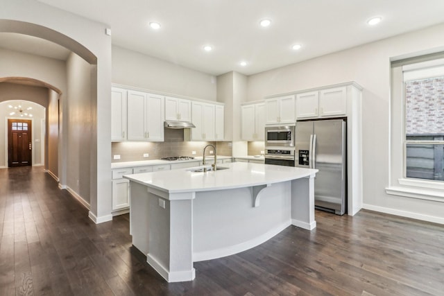 kitchen featuring dark wood-type flooring, white cabinets, a center island with sink, sink, and appliances with stainless steel finishes