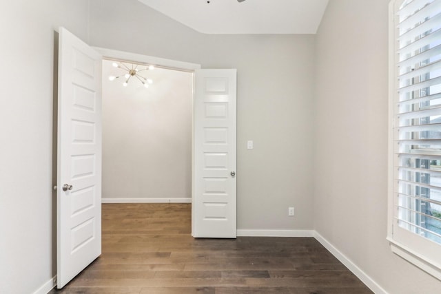 unfurnished bedroom with dark hardwood / wood-style floors and a notable chandelier