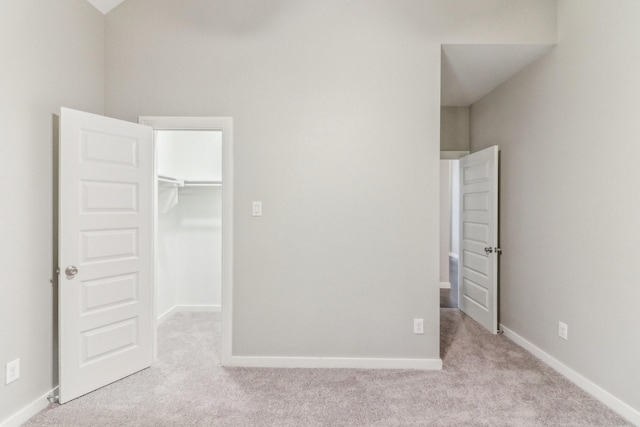 unfurnished bedroom with light colored carpet, a spacious closet, and a closet