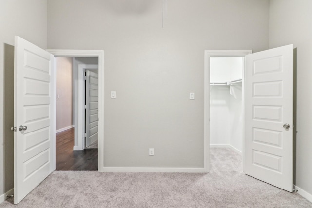 unfurnished bedroom featuring a walk in closet, light carpet, and a closet