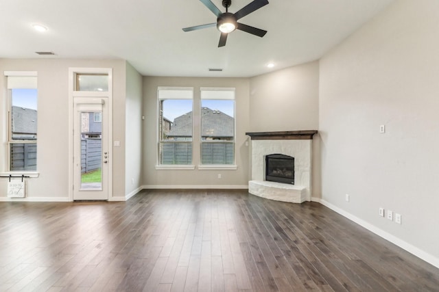 unfurnished living room featuring a fireplace, ceiling fan, and dark wood-type flooring