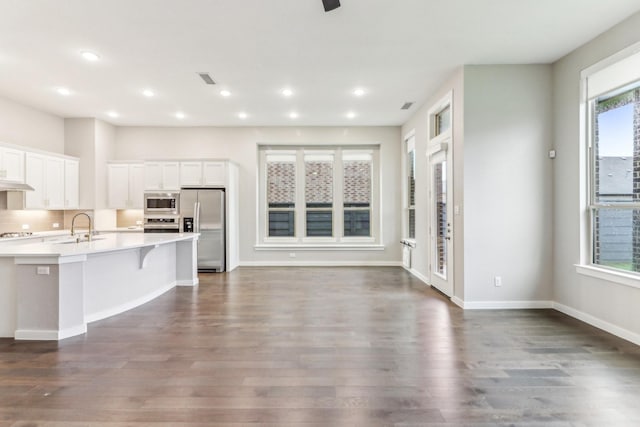 kitchen featuring dark wood-type flooring, white cabinets, a kitchen breakfast bar, sink, and stainless steel appliances