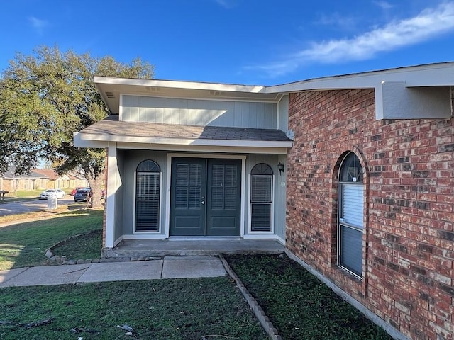 view of exterior entry featuring a lawn