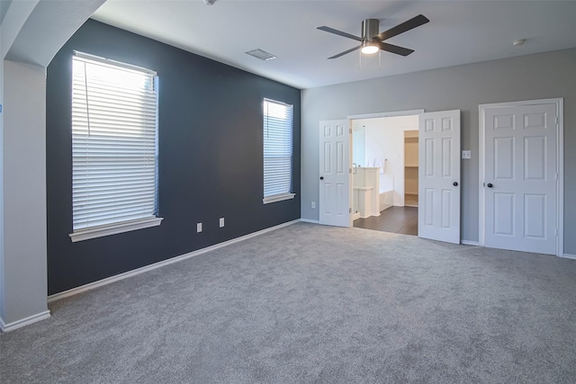 unfurnished bedroom with ceiling fan and dark colored carpet