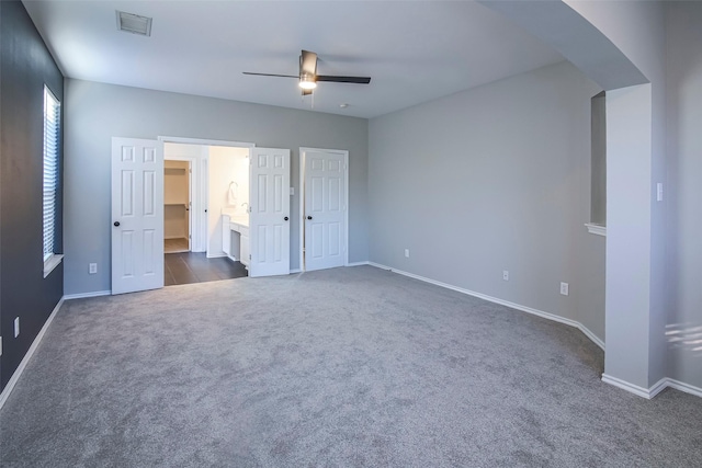 unfurnished bedroom featuring ceiling fan, dark carpet, and ensuite bathroom