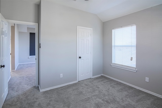 unfurnished bedroom featuring dark carpet, a closet, and lofted ceiling