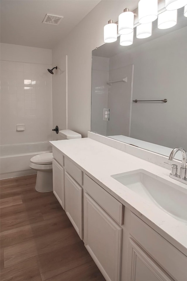 full bathroom with vanity, hardwood / wood-style floors, tiled shower / bath, and toilet