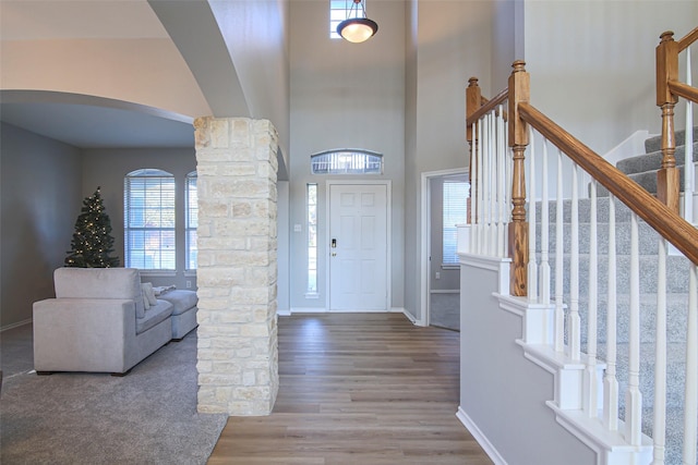 foyer with decorative columns, a high ceiling, and hardwood / wood-style flooring