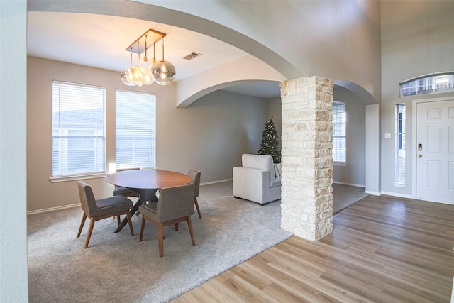 dining room featuring decorative columns, hardwood / wood-style flooring, and a notable chandelier