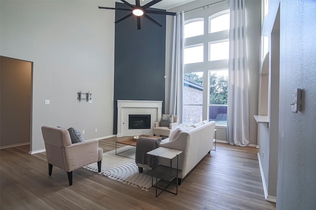 living room featuring wood-type flooring, ceiling fan, and a tiled fireplace