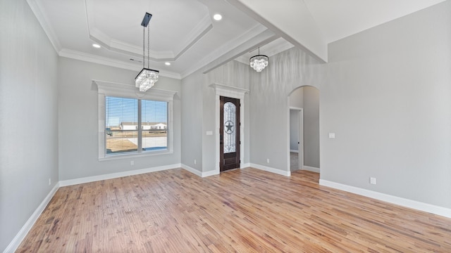 foyer with crown molding, light hardwood / wood-style flooring, a chandelier, and a tray ceiling